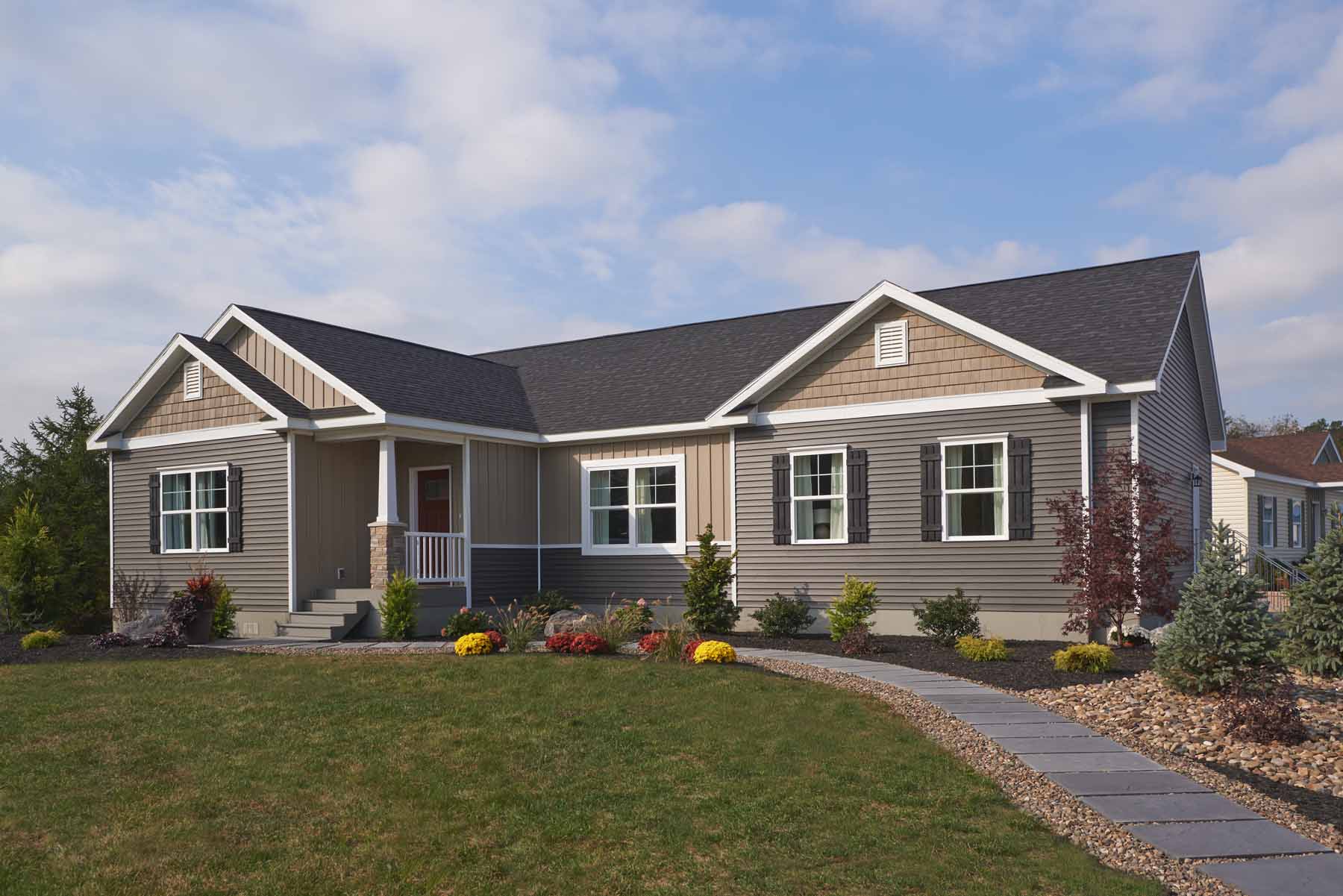One-story modular home with a welcoming front porch, curved walkway and colorful landscaped flower beds